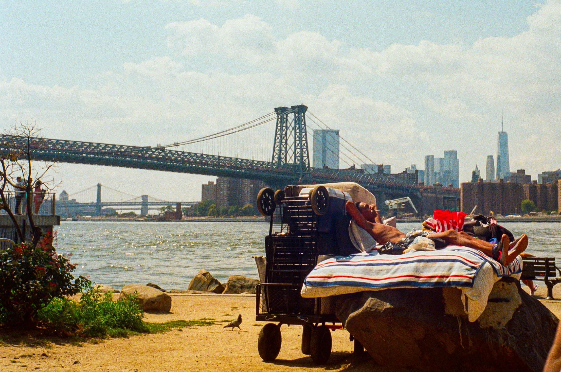 People relaxing by waterfront with bridge