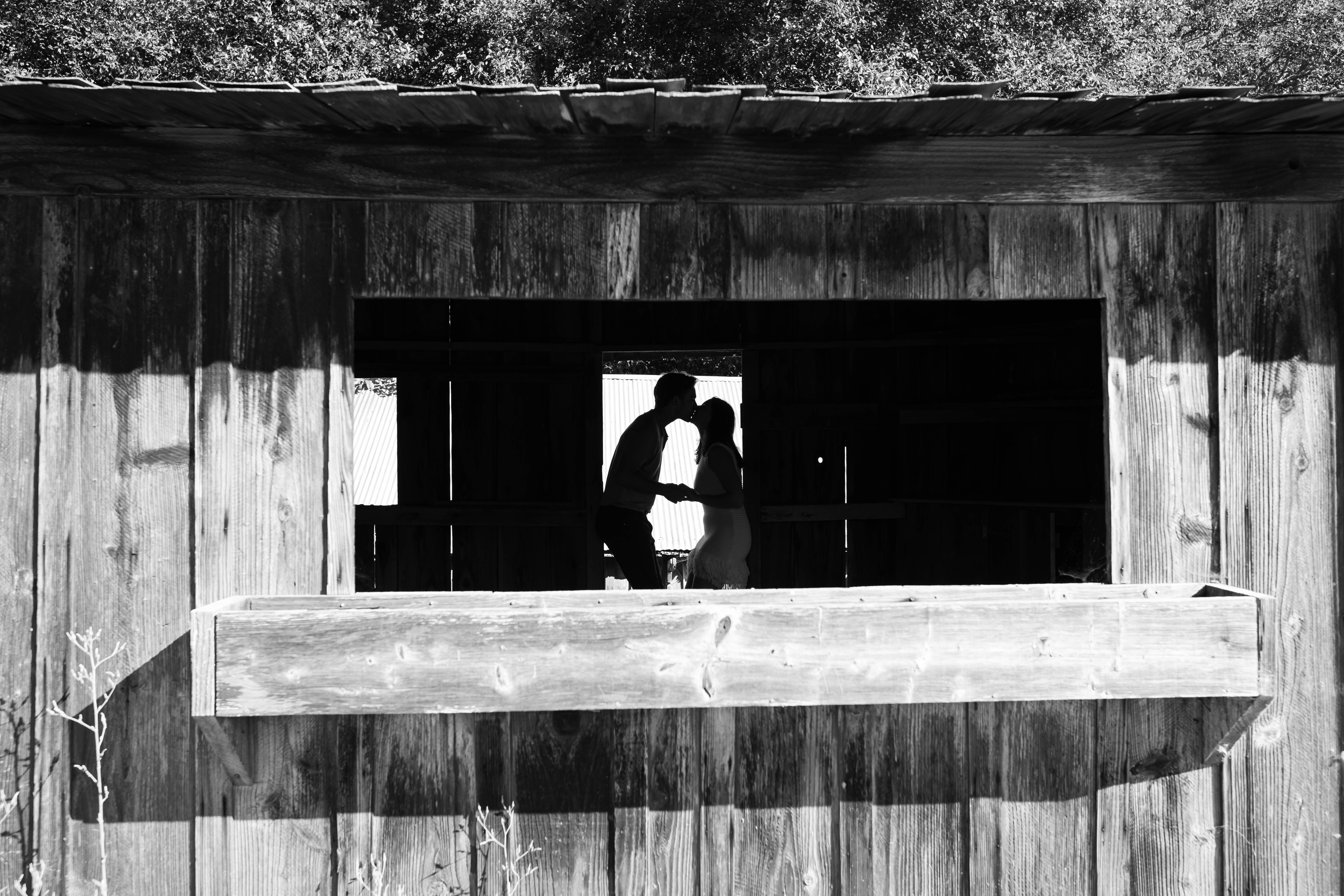 Black and white silhouette of couple in barn window