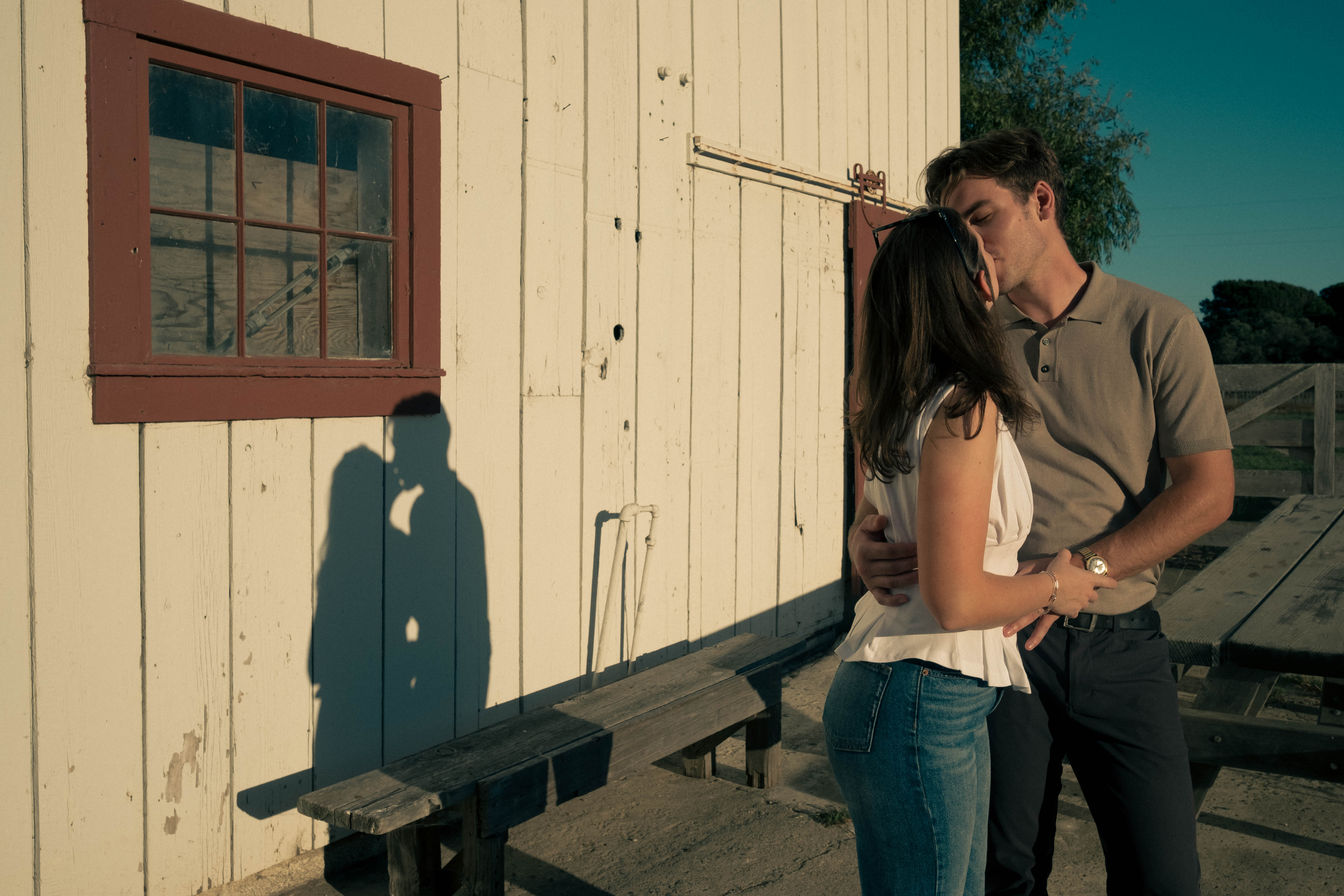 Couple embracing against white building with dramatic shadows
