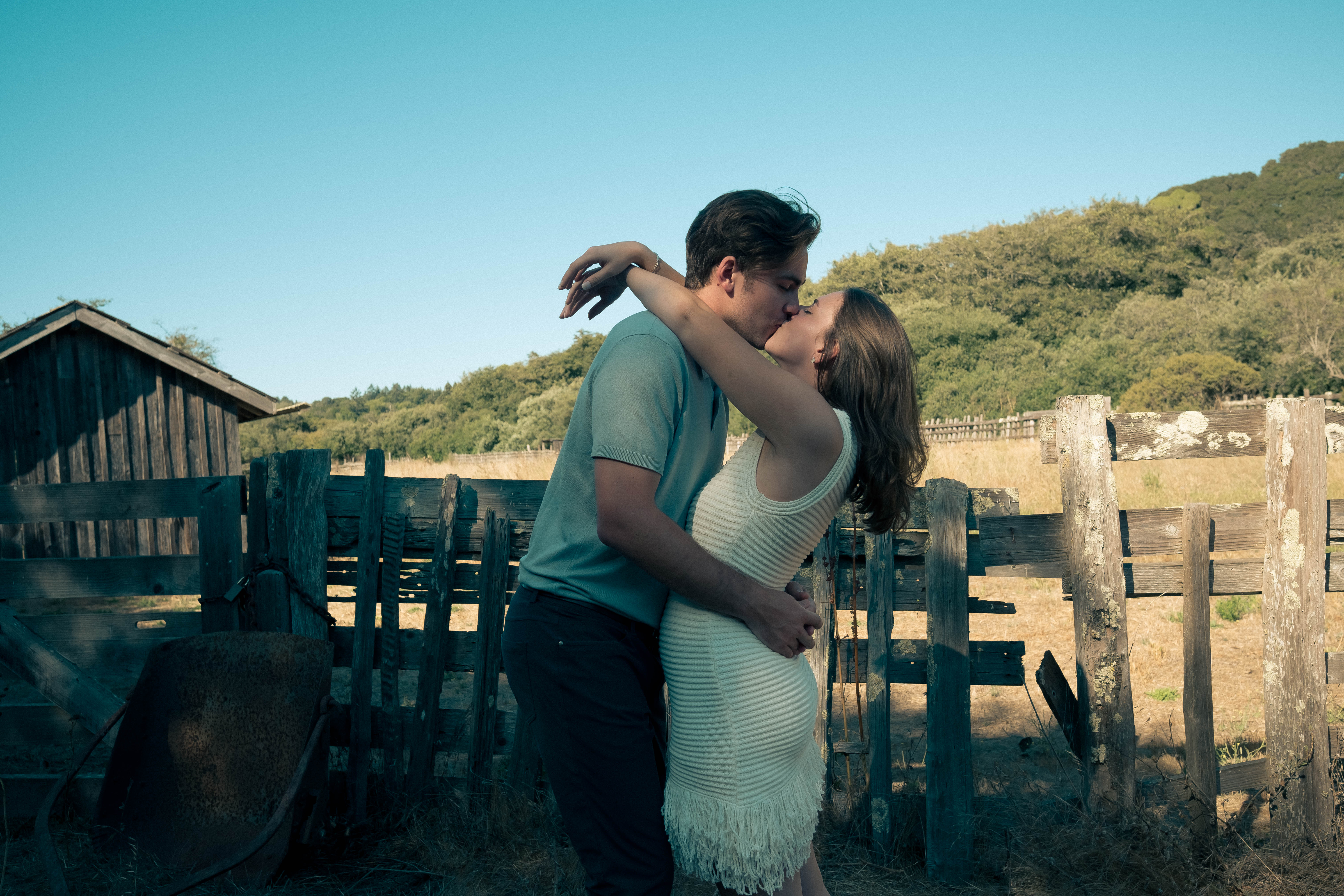 Couple kissing by rustic wooden structures